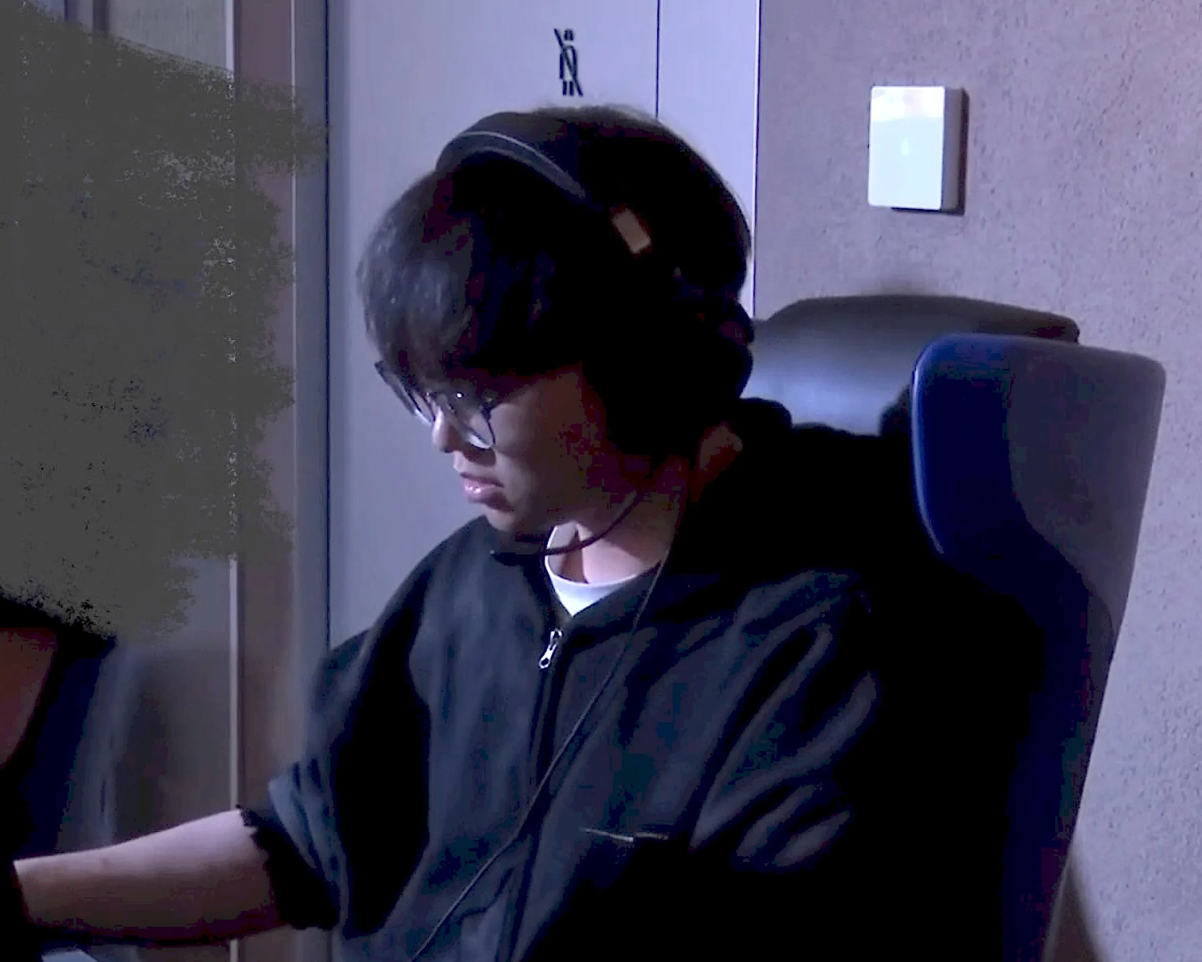 ALright at a LAN event, wearing a headset and glasses, playing at a tournament PC. A teammate beside him is painted over for privacy.